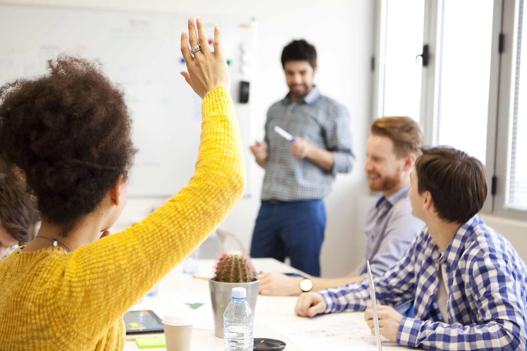 Teammate teaches while another teammate raises hand to ask question