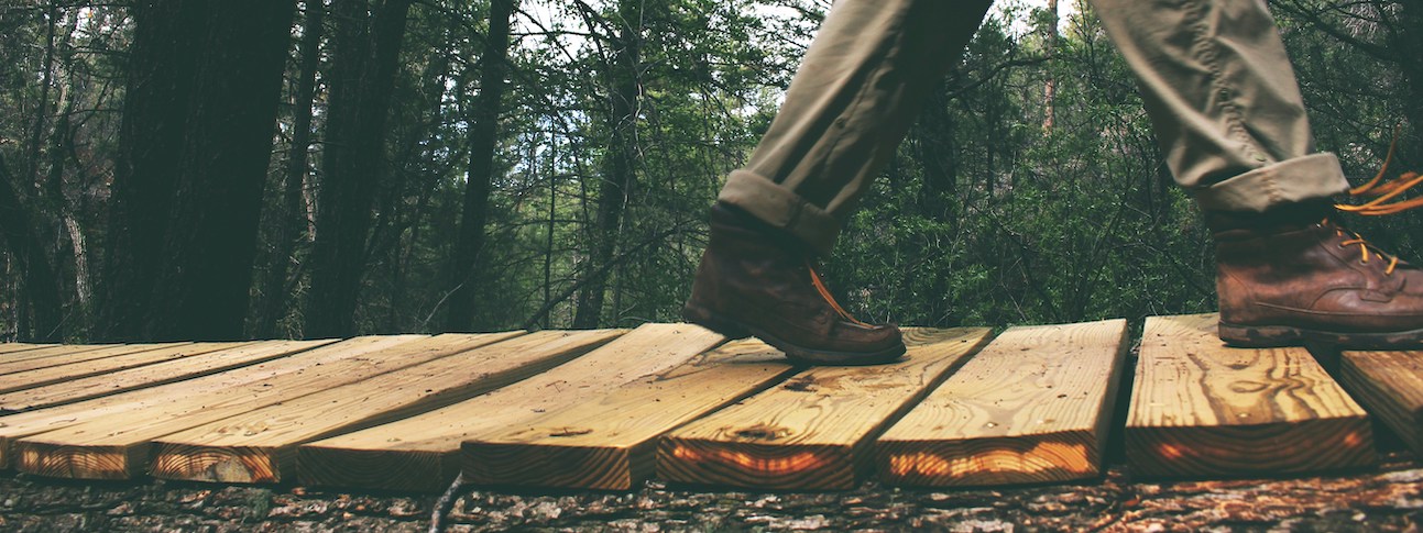 boots walking over a wooden bridge in nature