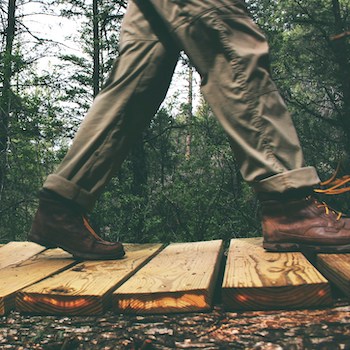 boots walking over a wooden bridge in nature