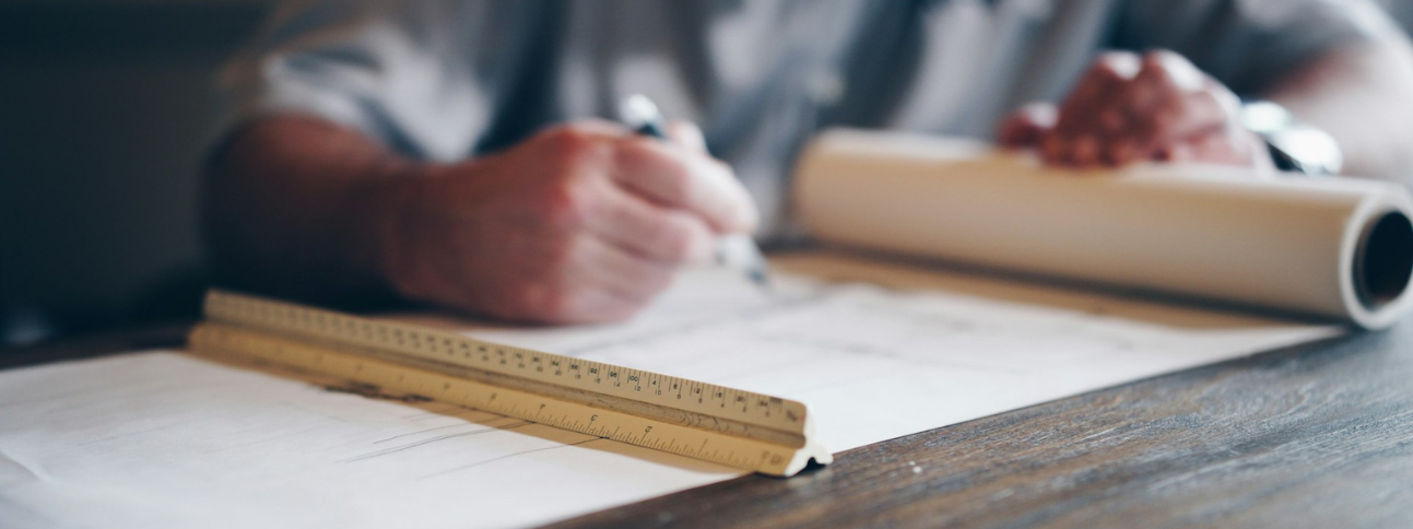 man drafting blueprint with ruler in the foreground